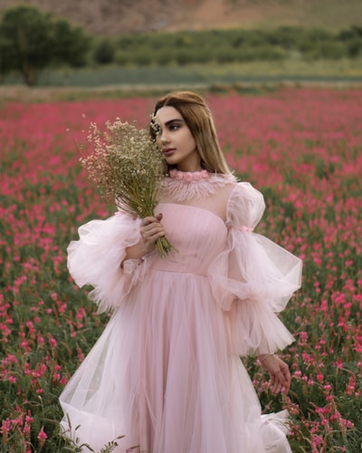 一个穿着粉红色衣服的女人手里拿着一束花